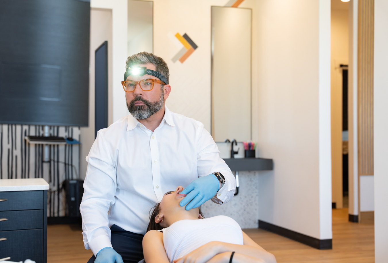 Scissortail orthodontist wearing loupes while examining a reclined patient in the treatment room.