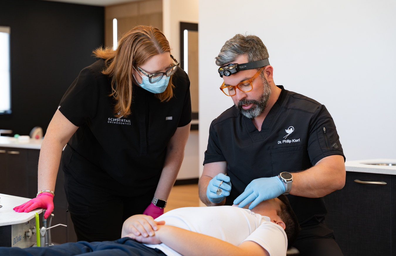 Scissortail Orthodontics doctor and assistant fitting an orthodontic appliance for a patient in the treatment chair.