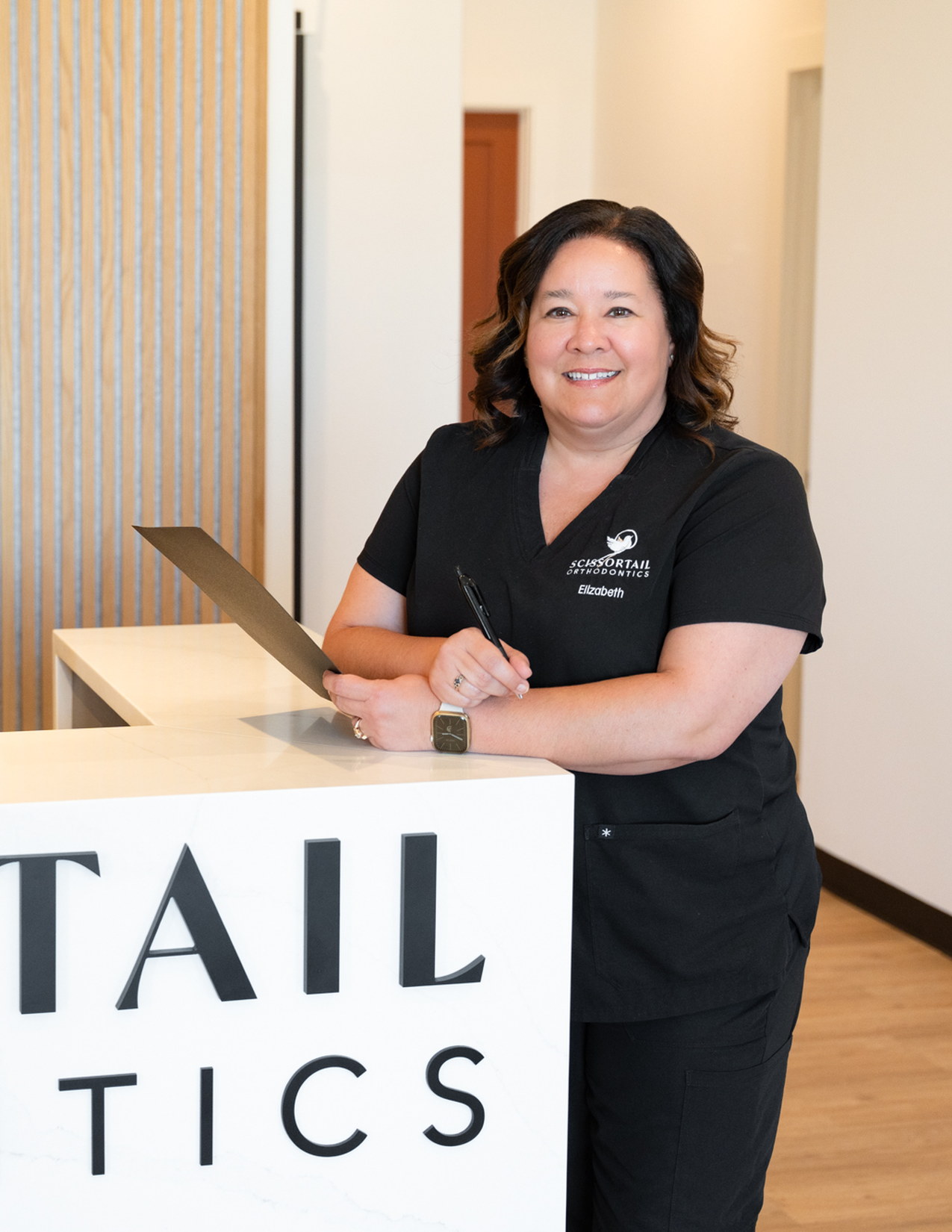Scissortail Orthodontics team member standing at the front desk ready to answer payment and financing questions.