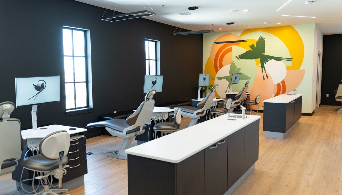 Orthodontic treatment chairs and monitors next to the colorful scissortail bird mural in the Scissortail Orthodontics office.